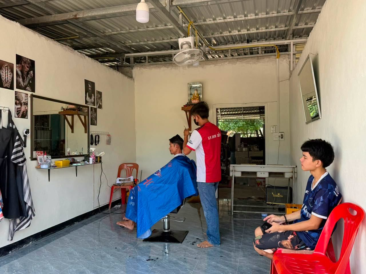 A young barber serving a customer in his business