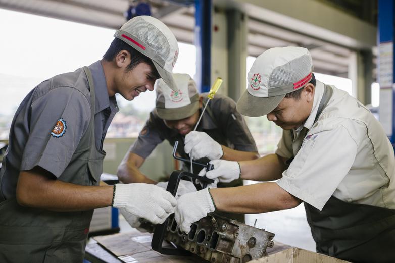 TVET instructors and trainees working together on an automotive engine