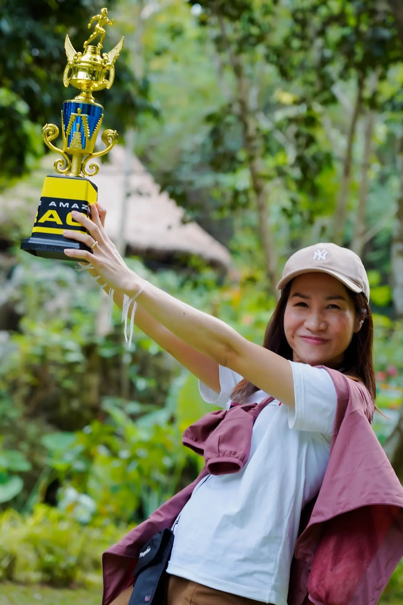 An Amazing Race participant celebrating with the trophy